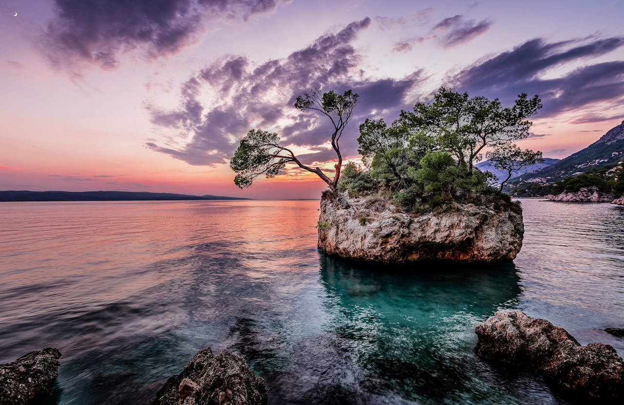 Beautiful sunset over a small tree-covered island in the Adriatic Sea, captured with vibrant colors.